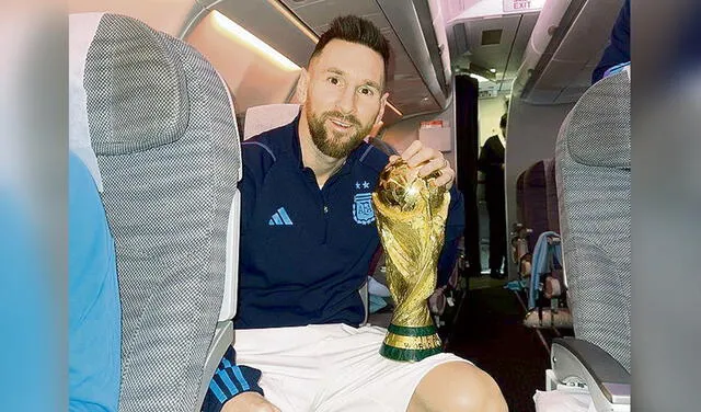Sueño cumplido. Messi en el avión de Qatar a Buenos Aires con su nuevo trofeo: la Copa del Mundo. Foto: difusión