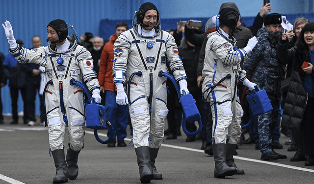 El multimillonario japonés Yusaku Maezawa (izquierda), su asistente Yozo Hirano (derecha) y el cosmonauta ruso Alexander Misurkin caminan antes del lanzamiento. Foto: AFP