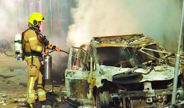 Un bombero apaga un auto incendiado en Rotterdam, Holanda.
