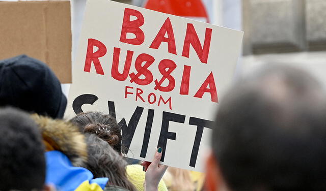 Un manifestante sostiene un cartel que dice "Prohibir a Rusia de SWIFT" durante una protesta contra la invasión rusa de Ucrania. Foto: AFP