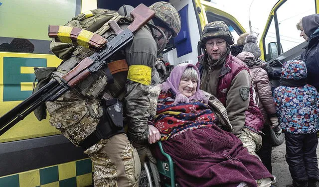Refugiados. Residentes y militares ayudan a una anciana a huir de la ciudad de Irpin, en Kiev. Foto: EFE