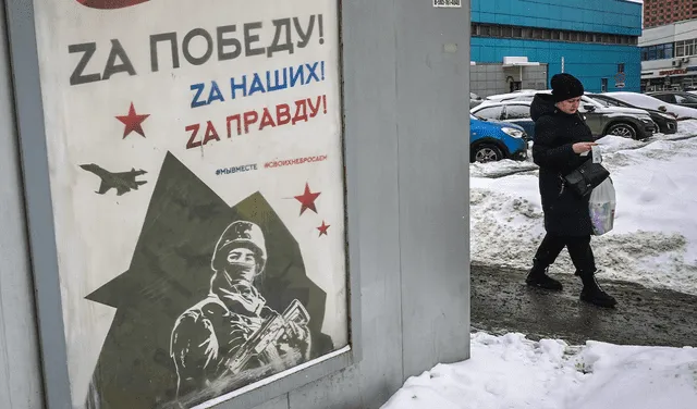 Una mujer pasa junto a un cartel dedicado al Día del Defensor de la Patria en Moscú. Foto: AFP   