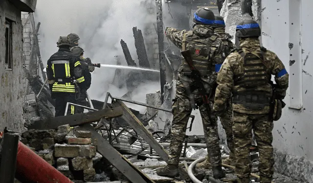 Policías ucranianos observan a los bomberos trabajando en una casa en llamas luego del bombardeo ruso en la ciudad de Kherson. Foto: AFP   