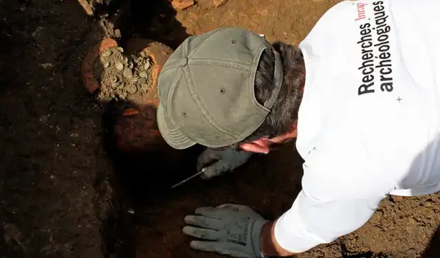 Un investigador excava uno de los tesoros de monedas de 1.800 años de antigüedad. Foto: INRAP Un investigador excava uno de los tesoros de monedas de 1.800 años de antigüedad. Foto: INRAP