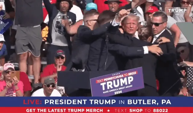 Tras el sonido de los disparos, Trump se incorporó en el escenario ya resguardado de la seguridad del evento. Foto: @dvorahfr/X.   