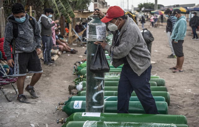 Un hombre carga un tanque de oxígeno vacío cuando llega a la cola para recargarlo en Villa El Salvador, sur de Lima. Foto: AFP
