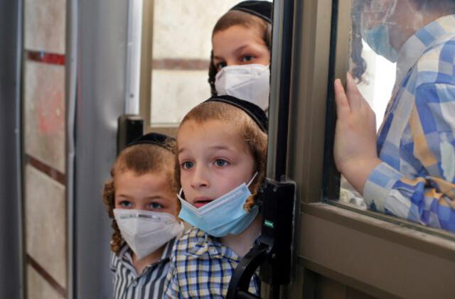 Niños vendo mientras le hacen pruebas de coronavirus a otros estudiantes en una escuela ultra ortodoxa de Israel. Foto: AFP