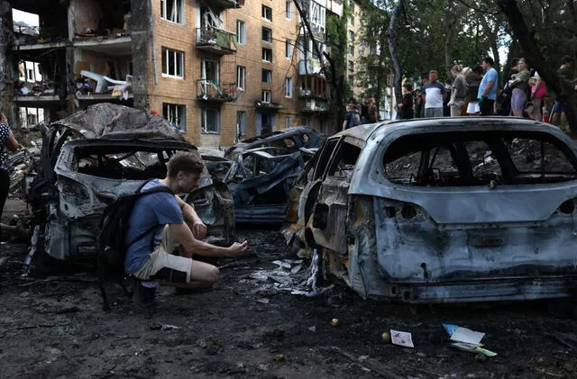 Un joven examina su coche destruido por el impacto de un misil en Kiev, el 8 de julio de 2024, en medio de la invasión rusa de Ucrania. Foto: AFP   