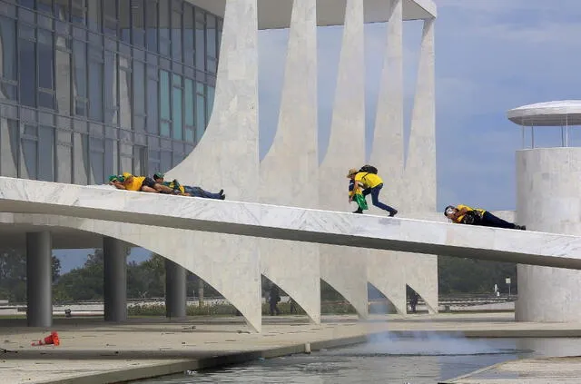 Simpatizantes del expresidente brasileño Jair Bolsonaro se cubren el rostro mientras invaden el Palacio Presidencial de Planalto el 8 de enero de 2023. Foto: AFP   