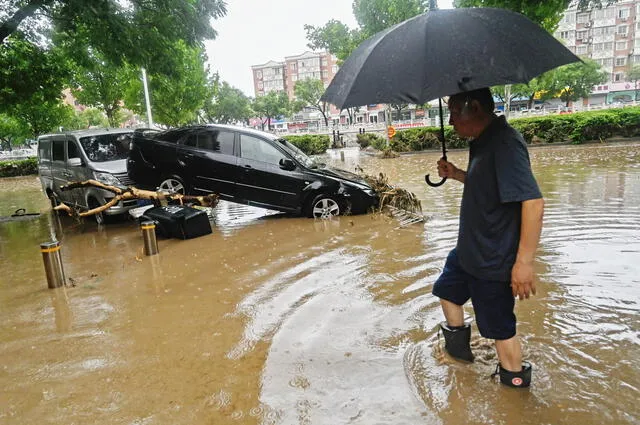 Un hombre junto con un coche dañado en una calle inundada por la llegada del tifón Doksuri. Foto: AFP   