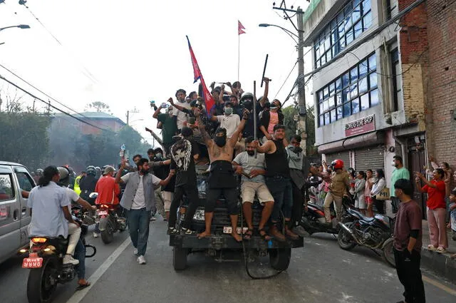 Manifestantes portan la bandera nacional de Nepal mientras viajan en un camión policial frente a la Casa Presidencial. Foto: AFP.   