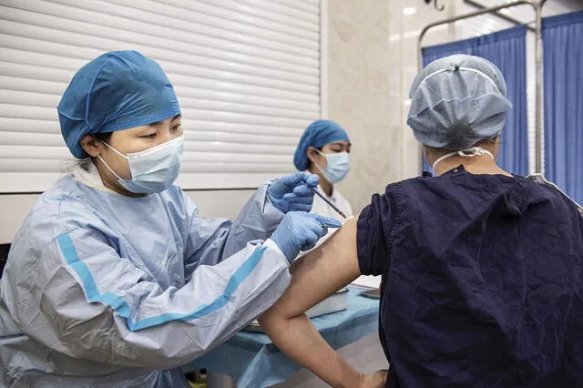Un miembro del personal médico (derecha) recibe una inyección de refuerzo de la vacuna contra el coronavirus Sinopharm en un hospital de Wuhan. Foto: AFP