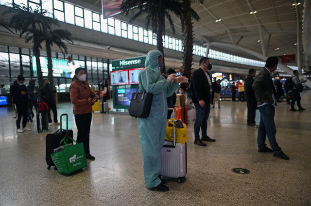 Una mujer que usa un traje de protección como medida preventiva contra la propagación del nuevo coronavirus COVID-19 espera para abordar un tren que se dirige a Shanghai, en China.