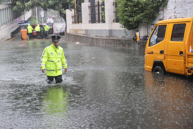 Un policía camina por una calle inundada a causa de las fuertes lluvias tras la llegada a tierra del tifón Doksuri, en Xiamen, China. Foto: AFP   