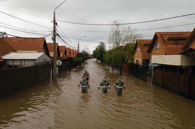 Rescatistas caminando por una calle inundada tras el desborde del río Claro, en la ciudad de Talca. Foto: EFE   