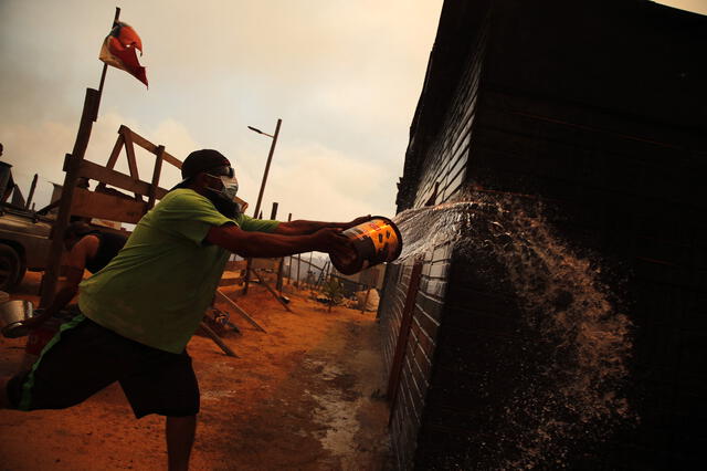 Ciudadano chileno intenta que el incendio forestal no queme su casa. Foto: AFP   