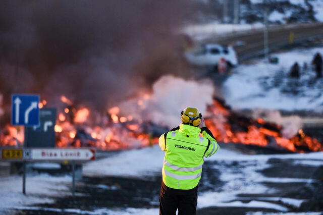 Un empleado de una agencia de carreteras toma una foto mientras se ve lava fundida desbordando la carretera que conduce al famoso destino turístico Blue Lagoon cerca de Grindavik. Foto: AFP   