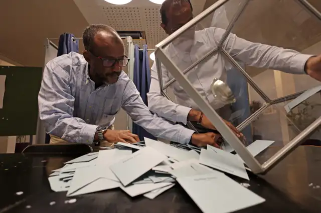 Funcionarios electorales vacían una urna para empezar a contar los votos de la segunda vuelta de las elecciones legislativas francesas en un colegio electoral de Le Port. Foto: AFP   