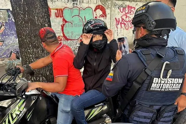 María Corina Machado siendo filmada por un agente de la Policía Nacional tras pronunciar un discurso durante una manifestación. Foto: AFP   