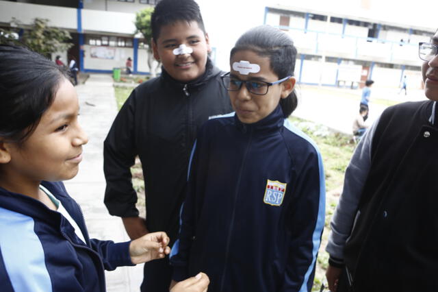 Una escolar pega una curita a su compañero con el mensaje: “Sangrar es normal”. Foto: Marco Cotrina / La República