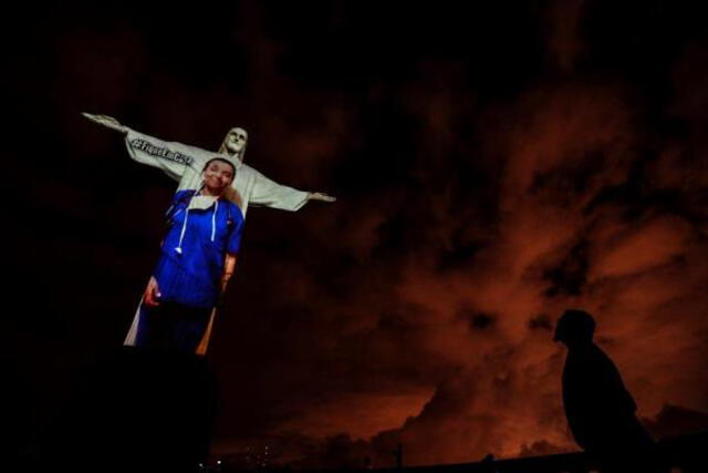Vista de la estatua del Cristo Redentor con una proyección de una trabajadora de la salud. Foto: EFE