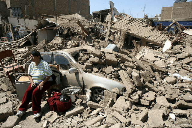  Una mujer sentada en la fachada de su casa derrumbada durante el terremoto de Pisco de 2007. Foto: AFP   