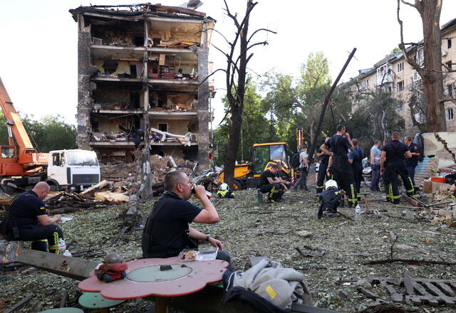 Rescatistas descansan mientras trabajan cerca de edificios de apartamentos y una guardería destruidos por un ataque con misiles en Kiev. Foto: AFP   
