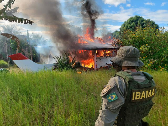 Miembro de la agencia ambiental mirando un avión perteneciente a mineros ilegales siendo consumido por el fuego durante una operación contra la deforestación del Amazonas, en el territorio yanomami. Foto: AFP   