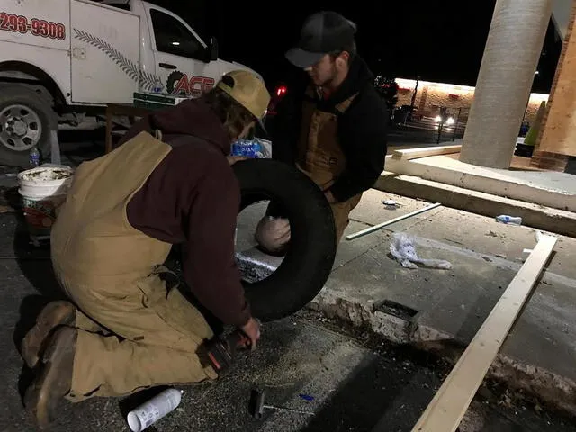 Los hermanos Heath (i) y Tristan (d) Hudson se afanan en mitad la noche del sábado y con una temperatura bajo cero en arreglar el neumático de una ambulancia en Mayfield, Kentucky.  Foto: EFE