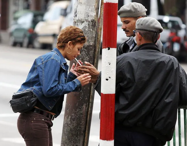 Policías cubanos le encienden un cigarrillo a una mujer en una calle del Vedado en La Habana en febrero de 2005.