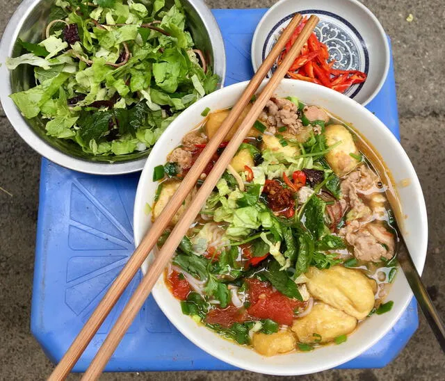 La comida callejera es un pilar de la vida diaria en Hanói. Es común ver pequeños puestos ofreciendo delicias como banh xeo (crepas de arroz crujiente) o banh ran (bolas de arroz fritas). Foto: CNN   