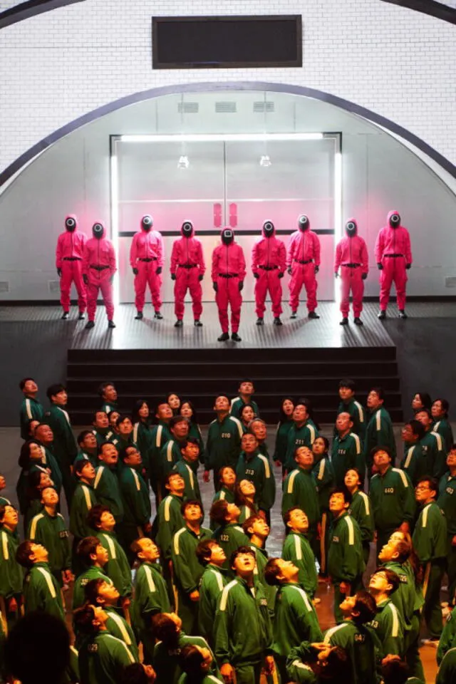 Squid Game: cuidadores de rosado intenso y participantes en uniformes verdes. Foto: Netflix