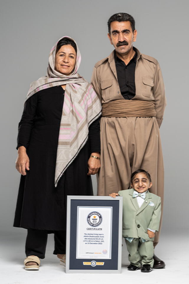Afshin Esmaeil Ghaderzadeh posa junto a sus padres y con su título del hombre más pequeño del mundo. Foto: Guinness World Records